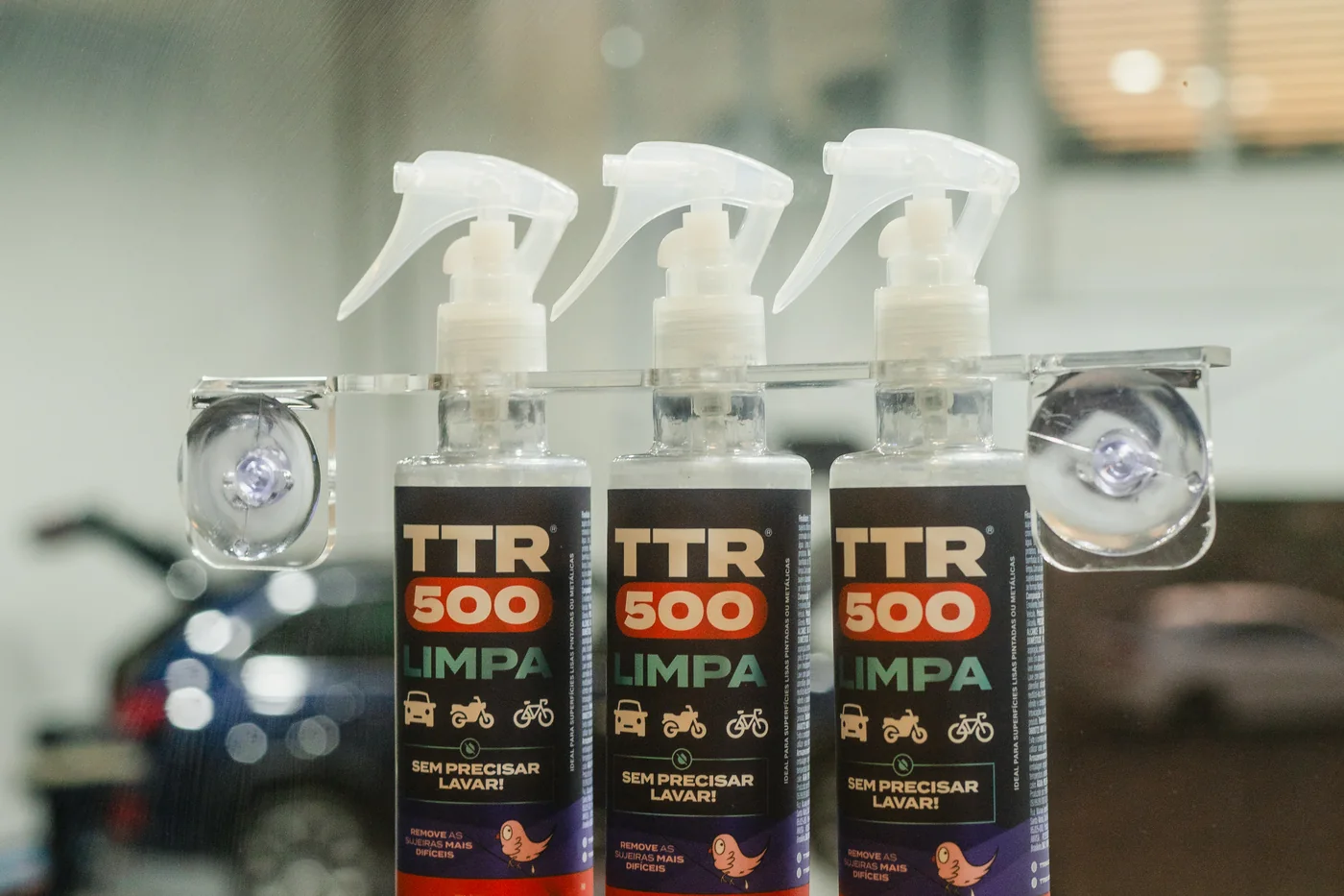 Expositor de vitrine com três frascos do TTR500 fixado no vidro de uma loja